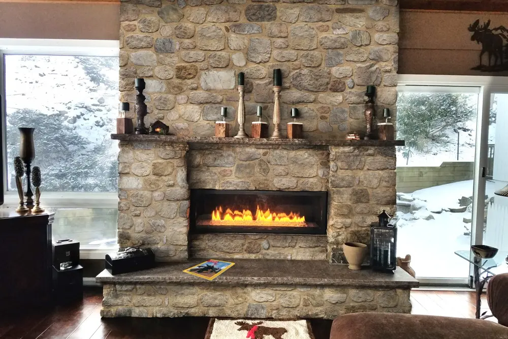Rustic fieldstone fireplace in a cottage with snowy views
