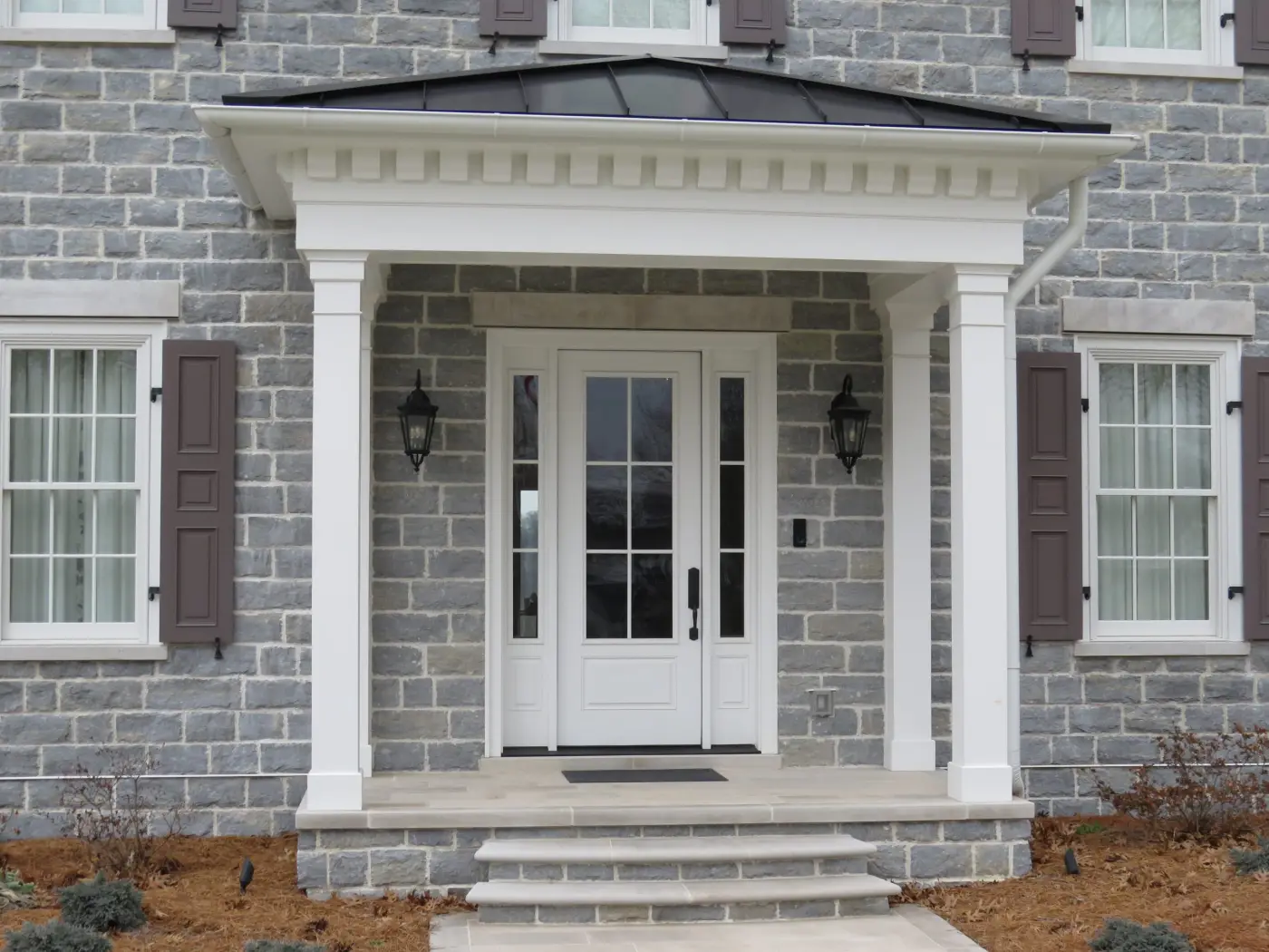 Grey stone entrance portico with white columns