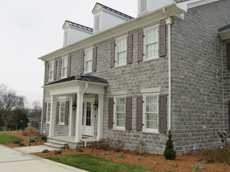 Colonial-style house in grey squared stone with white trim