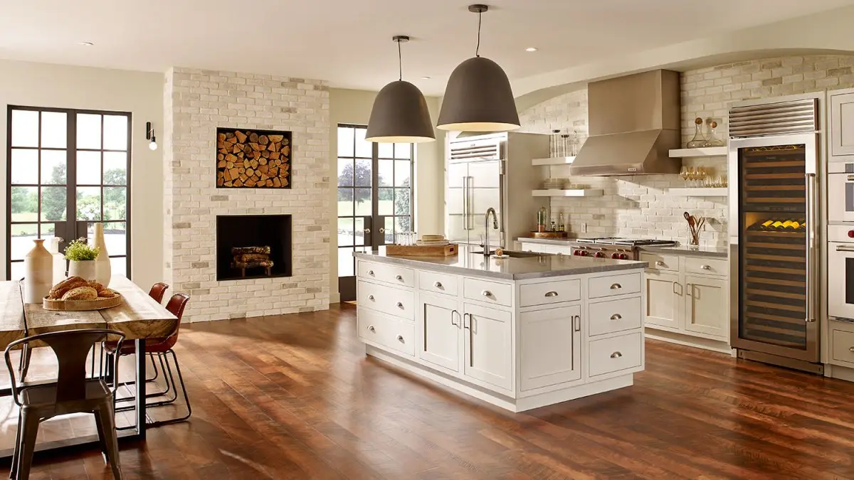 Open kitchen and dining room with a brick fireplace and log store